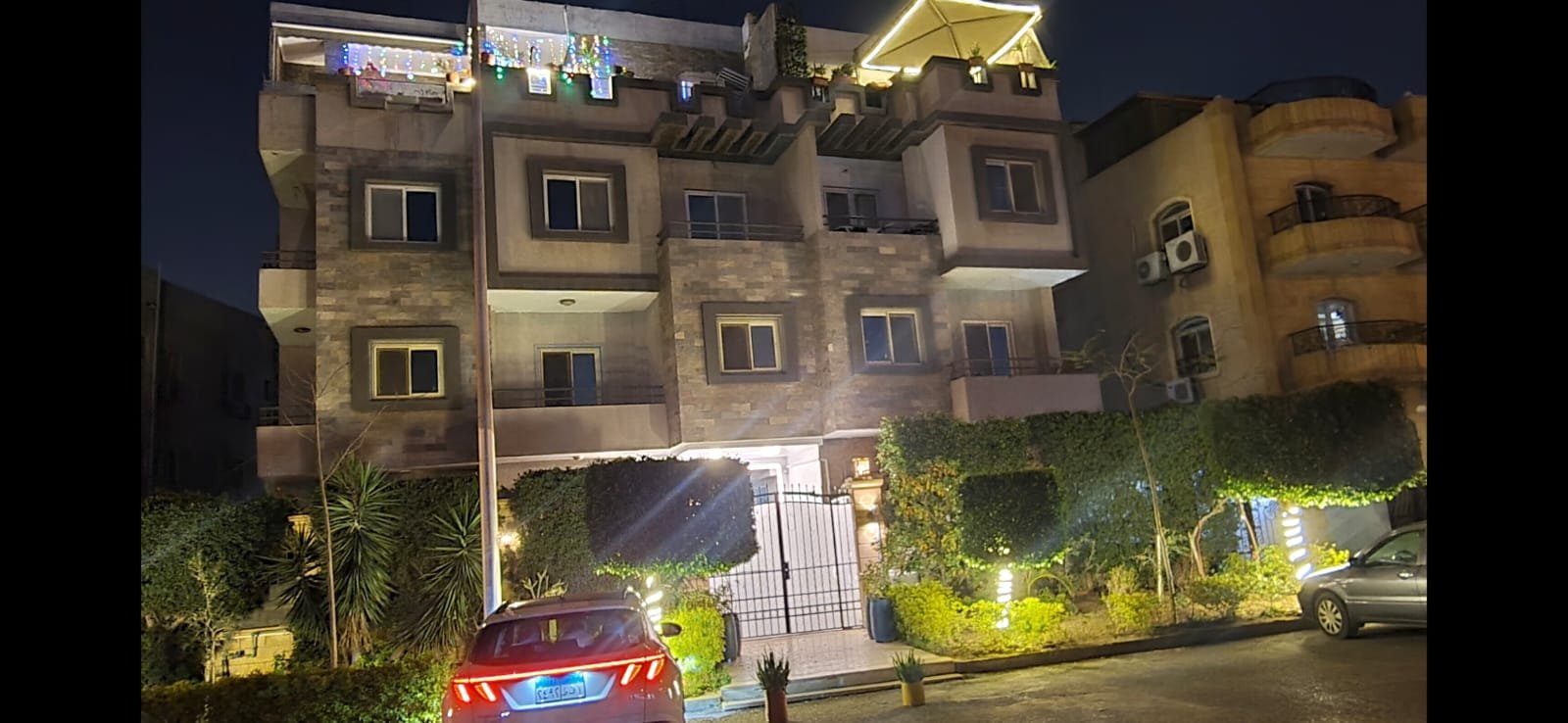 Residential building lit up at night with a parked car - unit in Al Banafseg 4, New Cairo