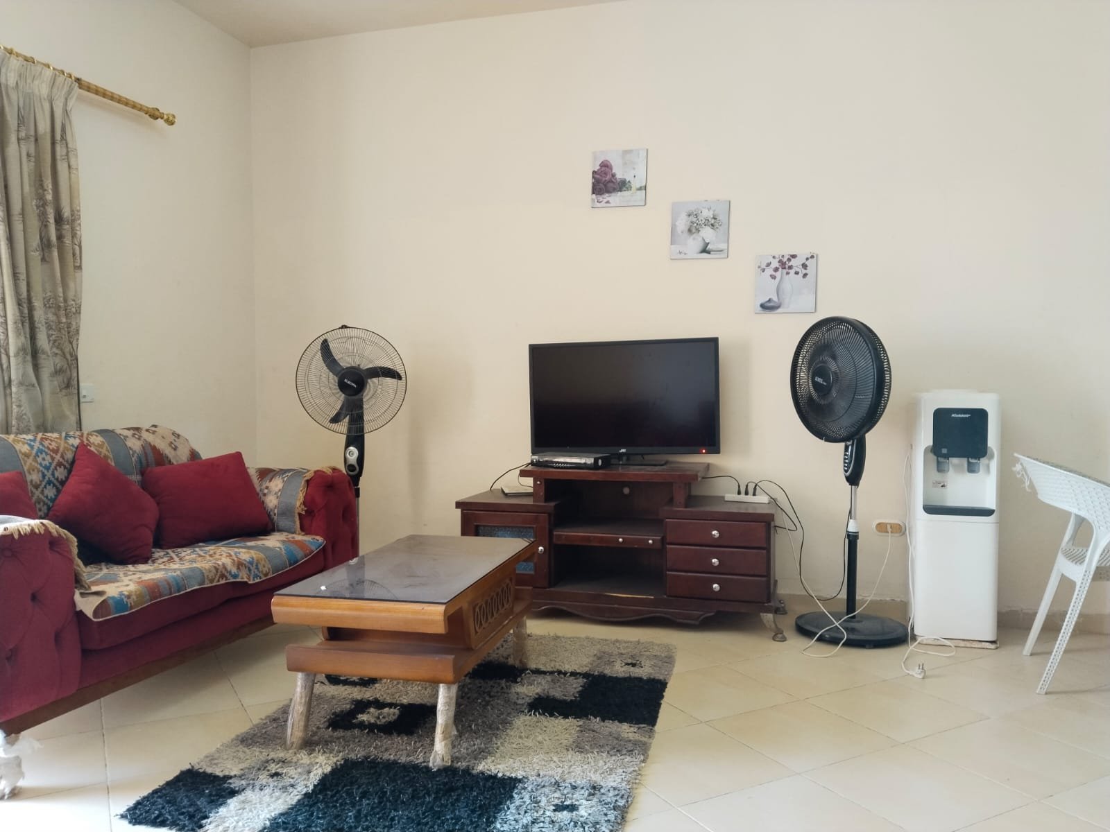 Living room with red sofa, TV and a water dispenser - chalet in Rozana, North Coast