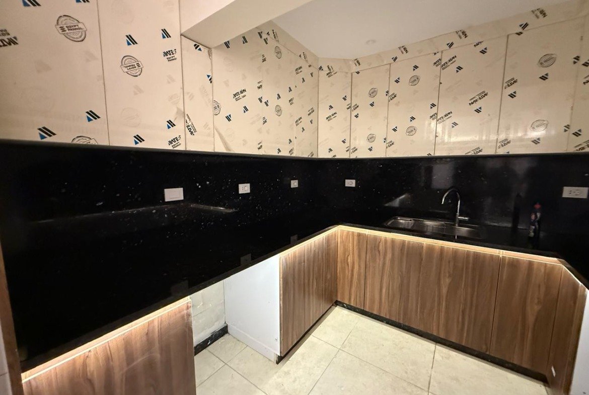 Bathroom wall with black tiles and a wooden panel strip - apartment in Sakan Compound, New Cairo