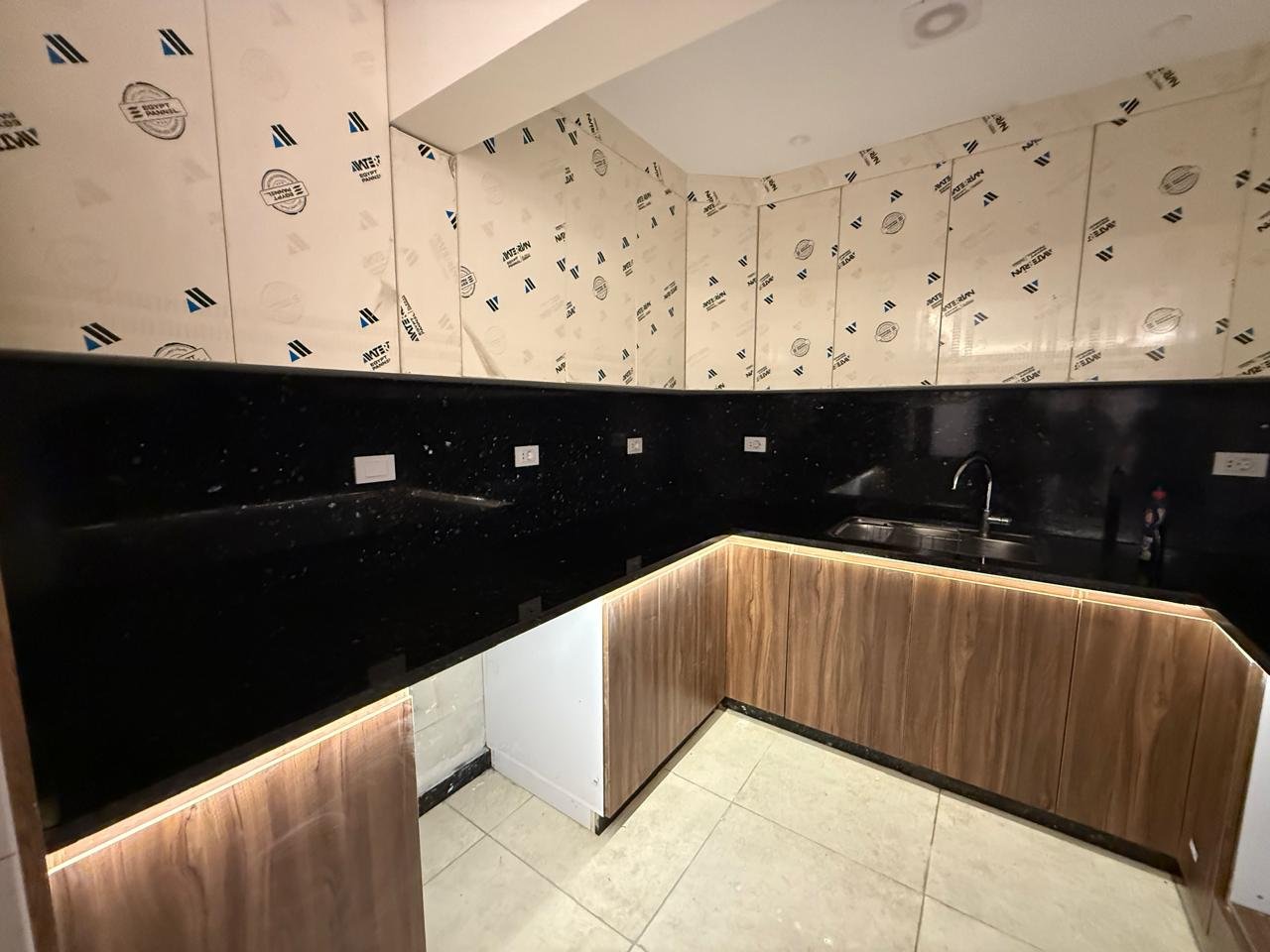 Bathroom wall with black tiles and a wooden panel strip - apartment in Sakan Compound, New Cairo