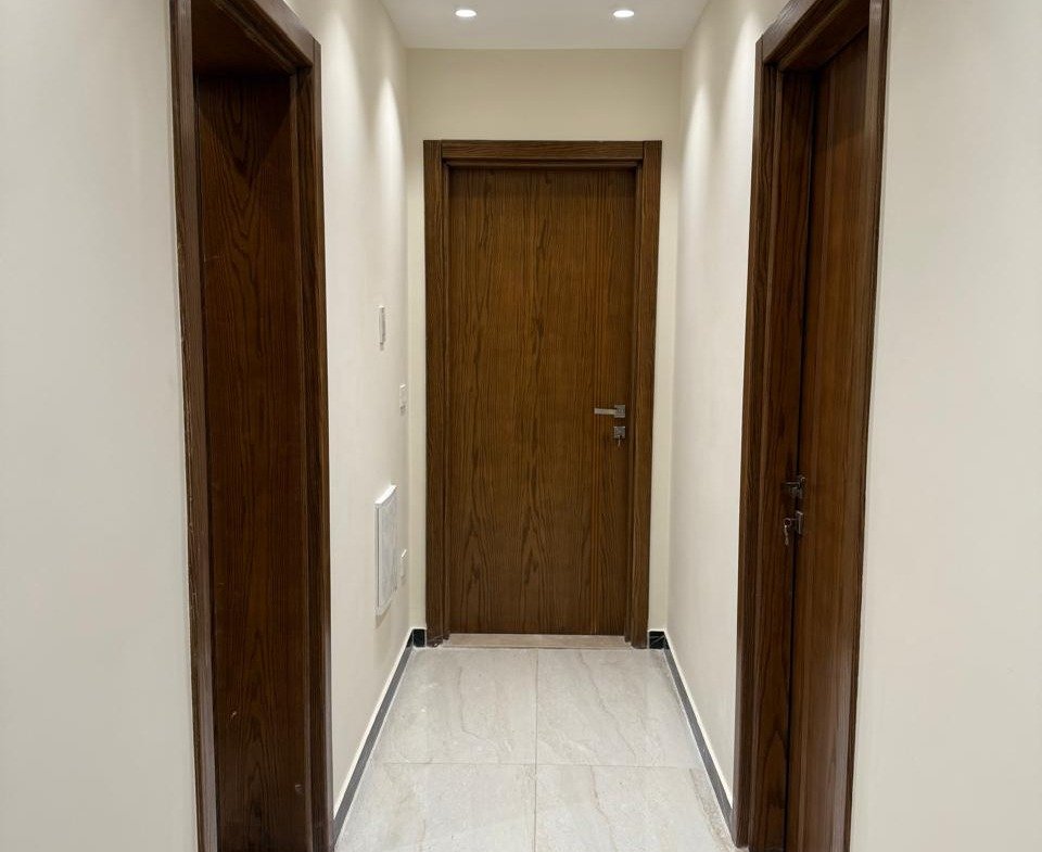 Corridor with wooden doors and a bright tile floor - apartment in Sakan Compound, New Cairo