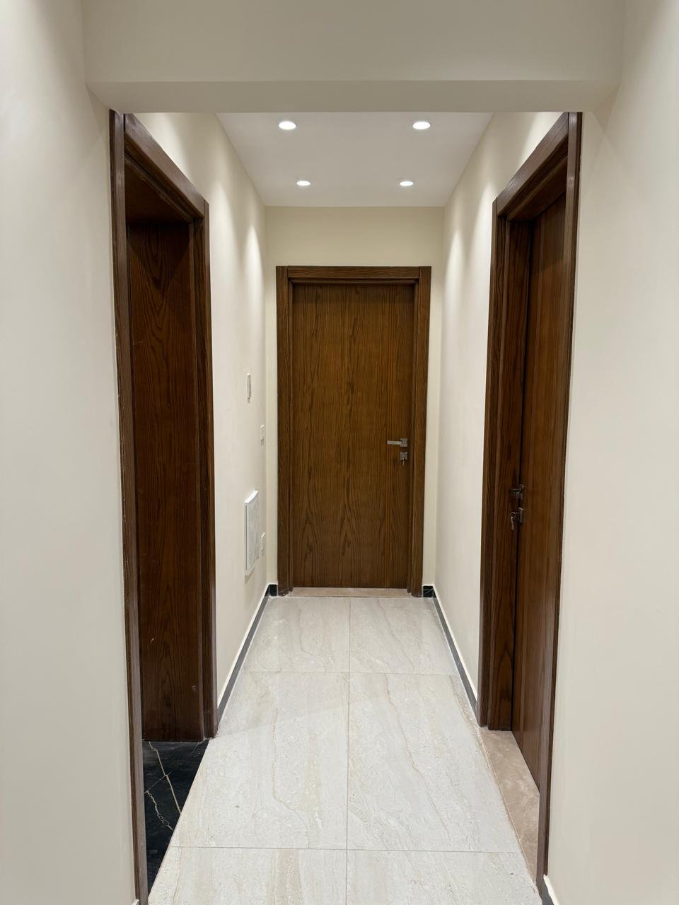 Corridor with wooden doors and a bright tile floor - apartment in Sakan Compound, New Cairo
