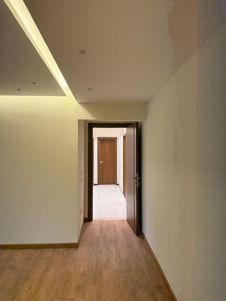 Parquet hallway opening onto another room - apartment in Sakan Compound, New Cairo