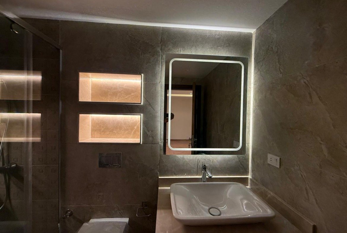 Bathroom with a lit niche, mirror and glass shower screen - apartment in Sakan Compound, New Cairo