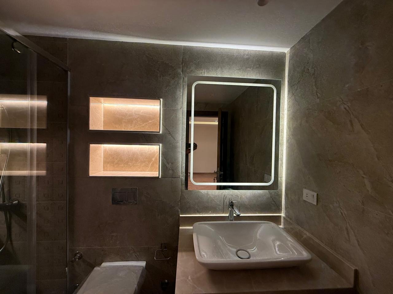 Bathroom with a lit niche, mirror and glass shower screen - apartment in Sakan Compound, New Cairo