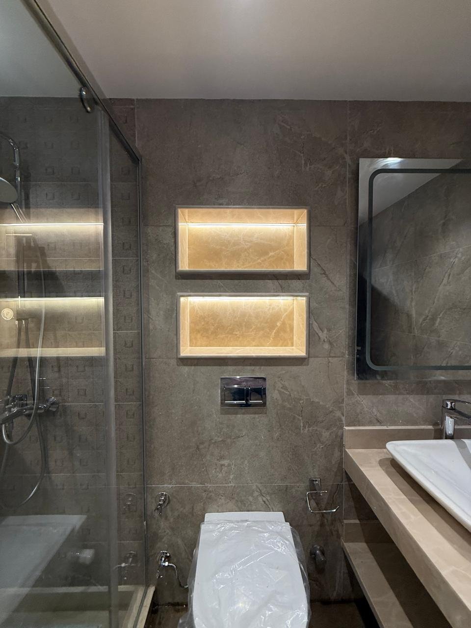 Toilet and basin beside lit wall niches - apartment in Sakan Compound, New Cairo
