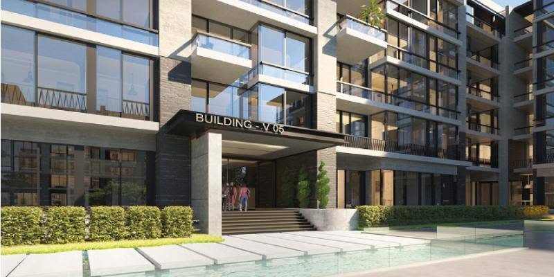 Building entrance with a pool in front and a landscaped hedge - apartment in The View by Waterway, New Cairo