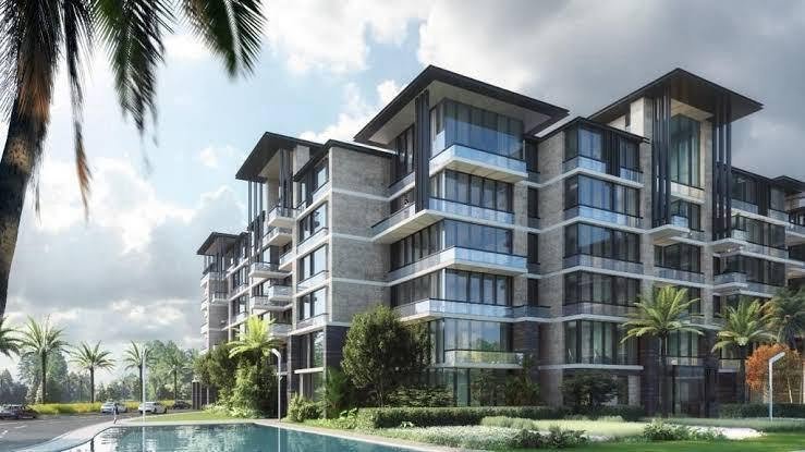 Modern apartment blocks with balconies behind a pool and palm trees - apartment in The View by Waterway, New Cairo