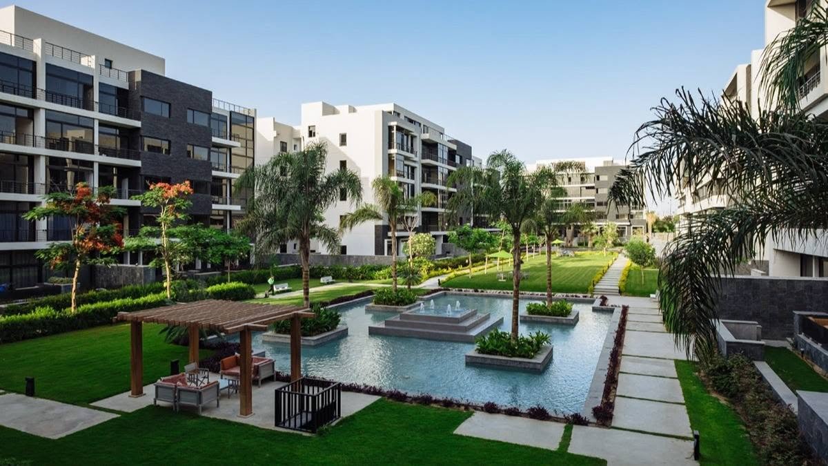 Garden with a pergola, pond and paved paths between apartment blocks - apartment in The View by Waterway, New Cairo
