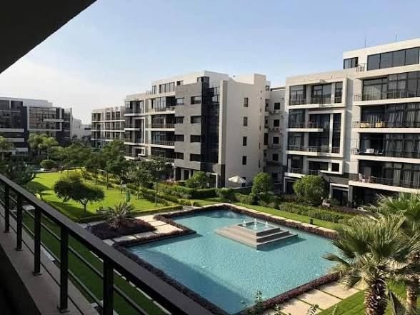 View from a balcony over a pool with a fountain and apartment blocks - apartment in The View by Waterway, New Cairo