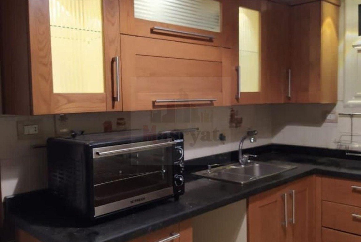 Kitchen with wooden cabinets and a toaster oven - apartment in 3rd District, New Cairo