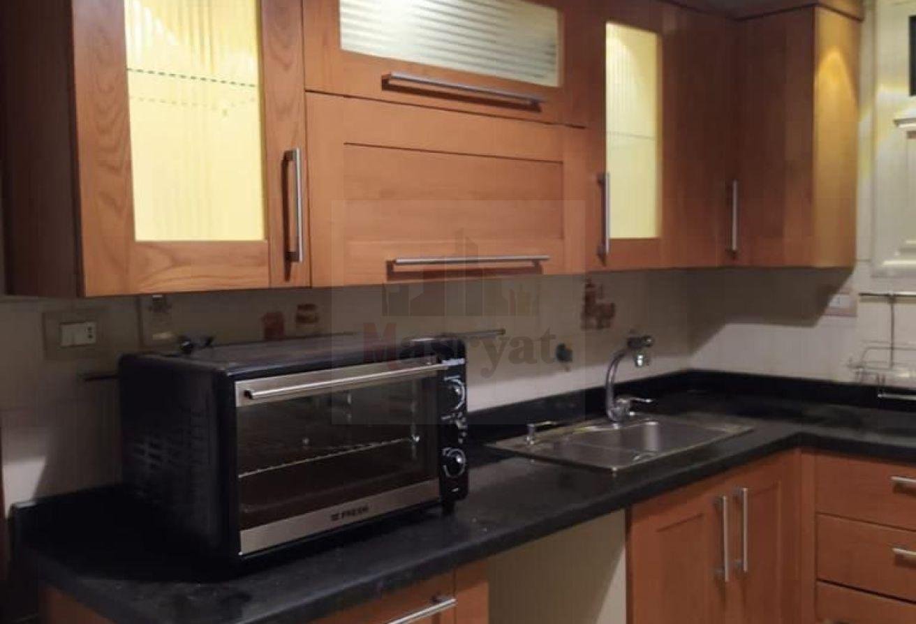 third-district-apt-135-05 Kitchen with wooden cabinets and a toaster oven - apartment in 3rd District, New Cairo
