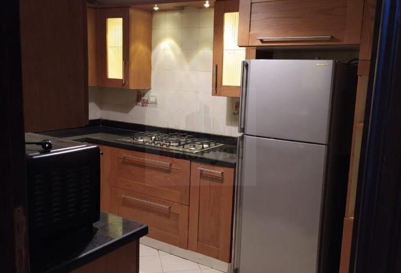 third-district-apt-135-08 Kitchen corner with a silver refrigerator and wooden cabinets - apartment in 3rd District, New Cairo