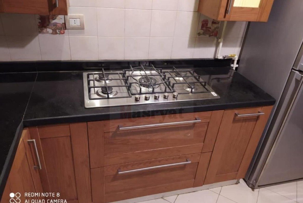Gas hob set into a black kitchen counter - apartment in 3rd District, New Cairo