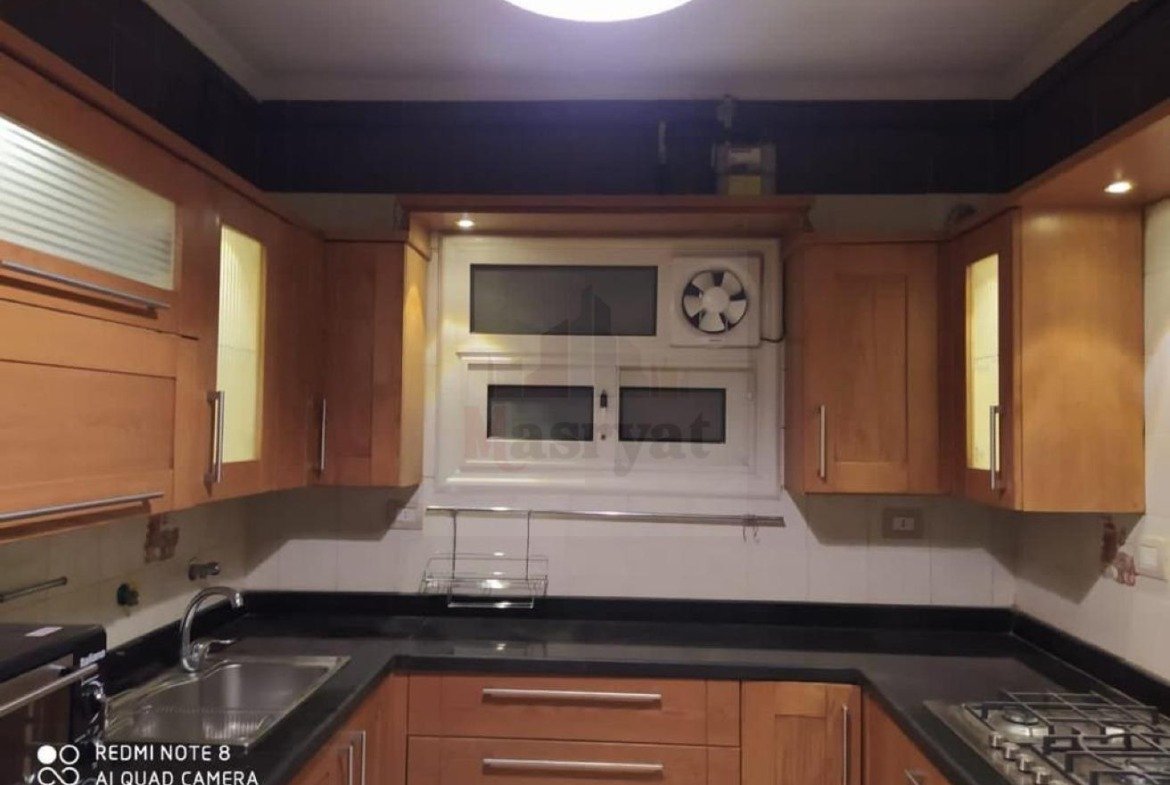 Kitchen with sink, extractor fan and wood cabinets - apartment in 3rd District, New Cairo