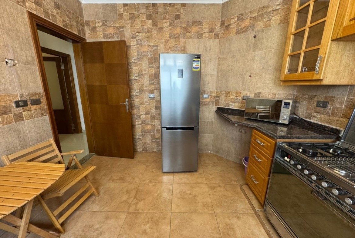 Kitchen with a steel fridge and wooden cabinets - apartment in El Yasmeen 4, New Cairo