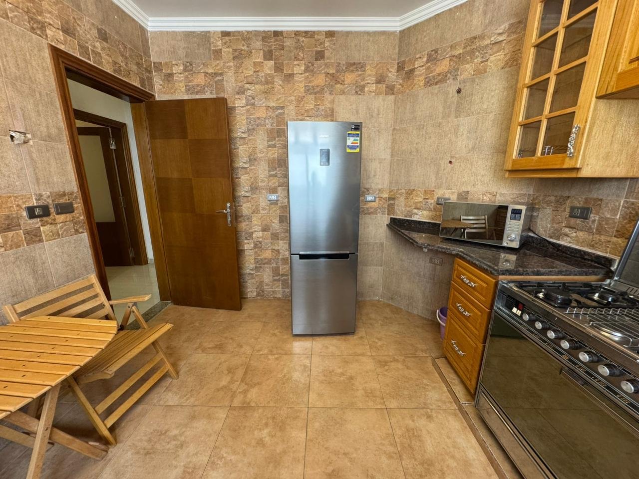Kitchen with a steel fridge and wooden cabinets - apartment in El Yasmeen 4, New Cairo