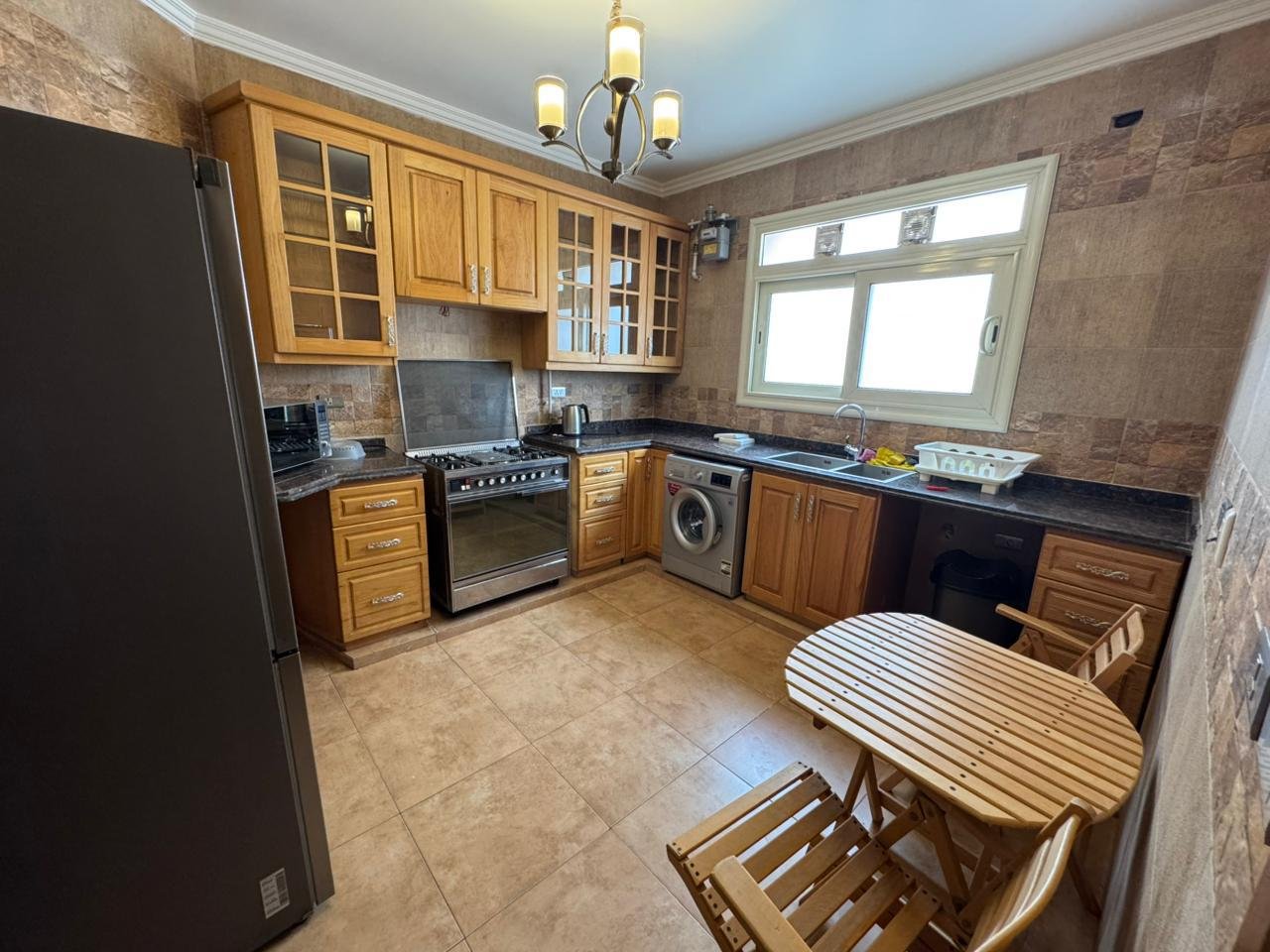 Kitchen with a round wooden table and a washing machine - apartment in El Yasmeen 4, New Cairo