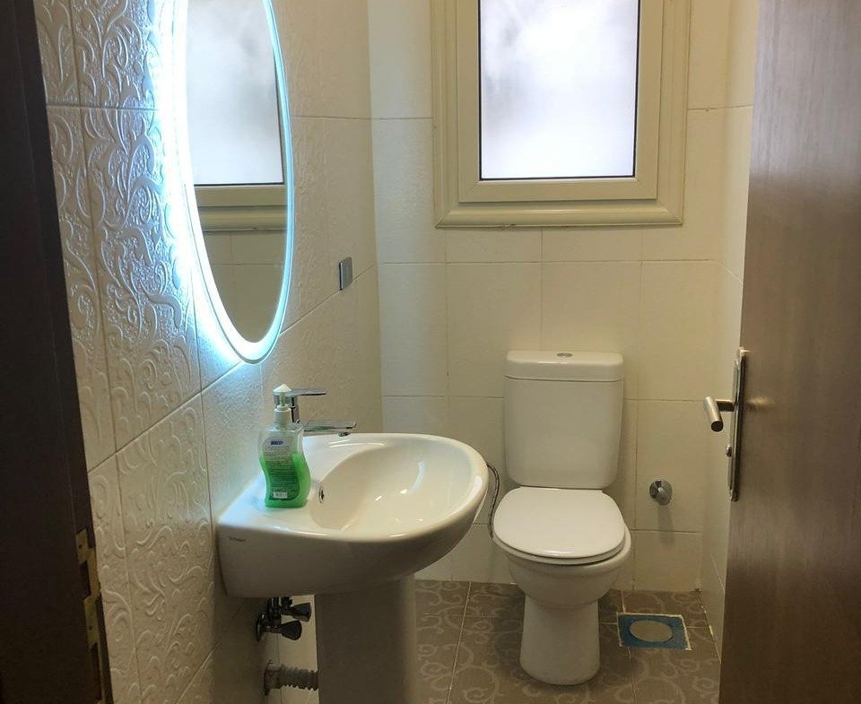 Guest bathroom with a round lit mirror and a pedestal basin - apartment in El Yasmeen 4, New Cairo