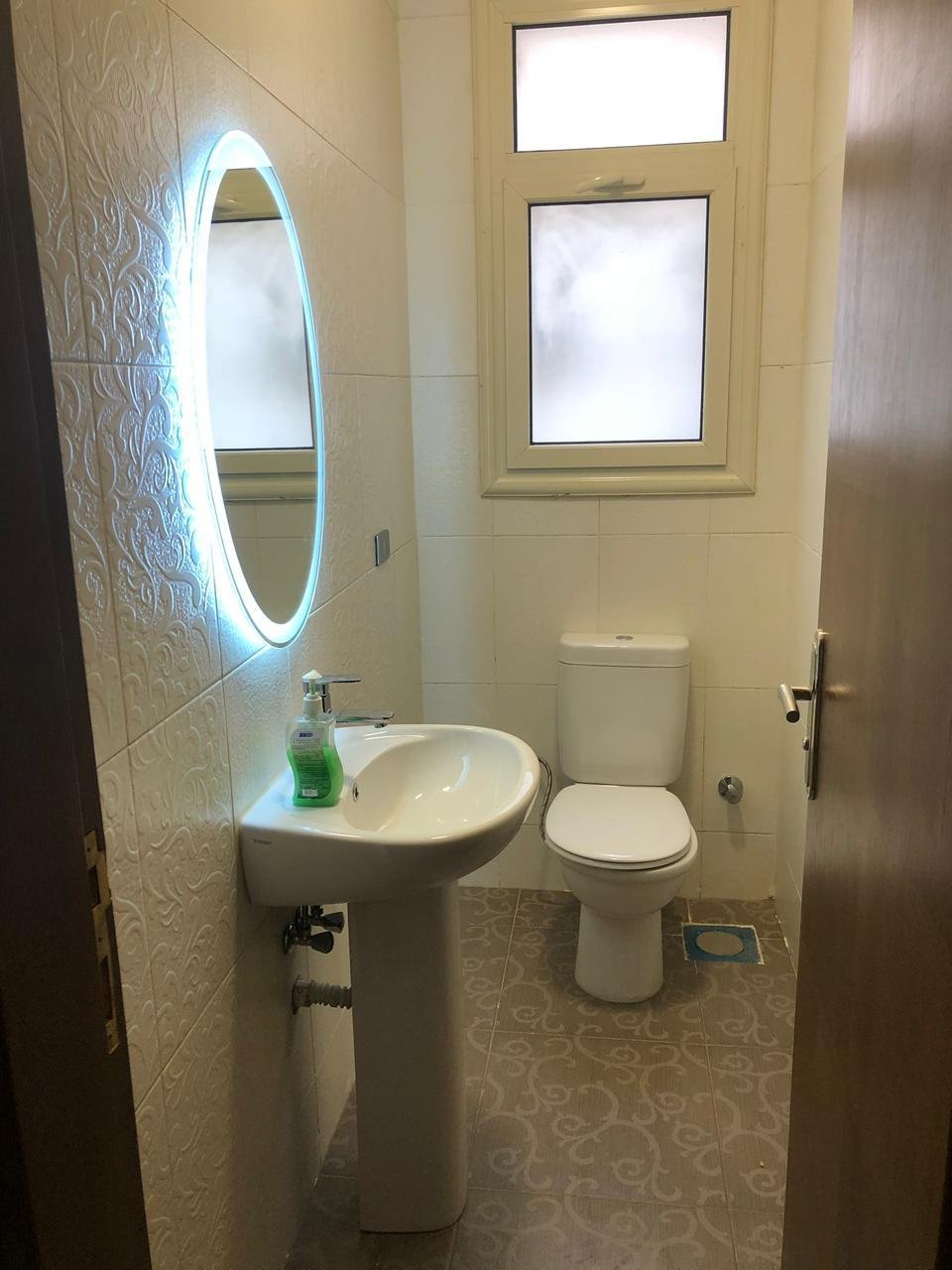 Guest bathroom with a round lit mirror and a pedestal basin - apartment in El Yasmeen 4, New Cairo